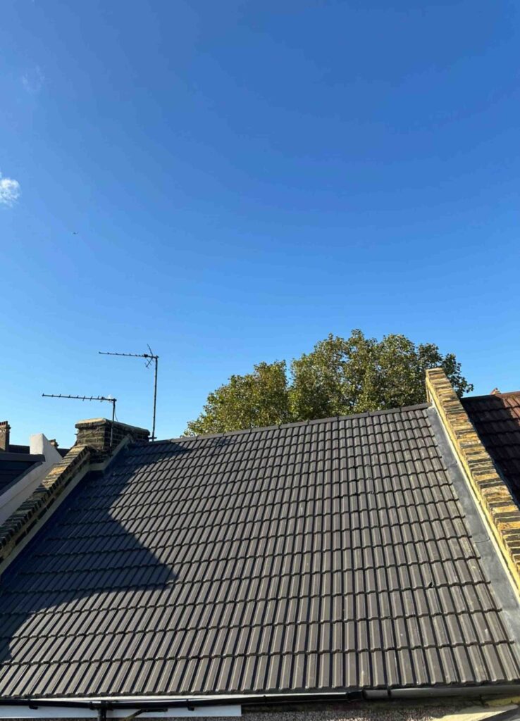 a pitched roof made of dark gray tiles on a building under a clear, bright blue sky