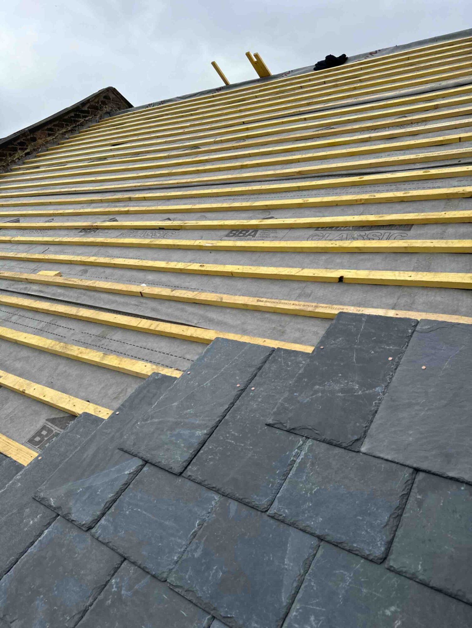 slate roof, highlighting both the completed section
