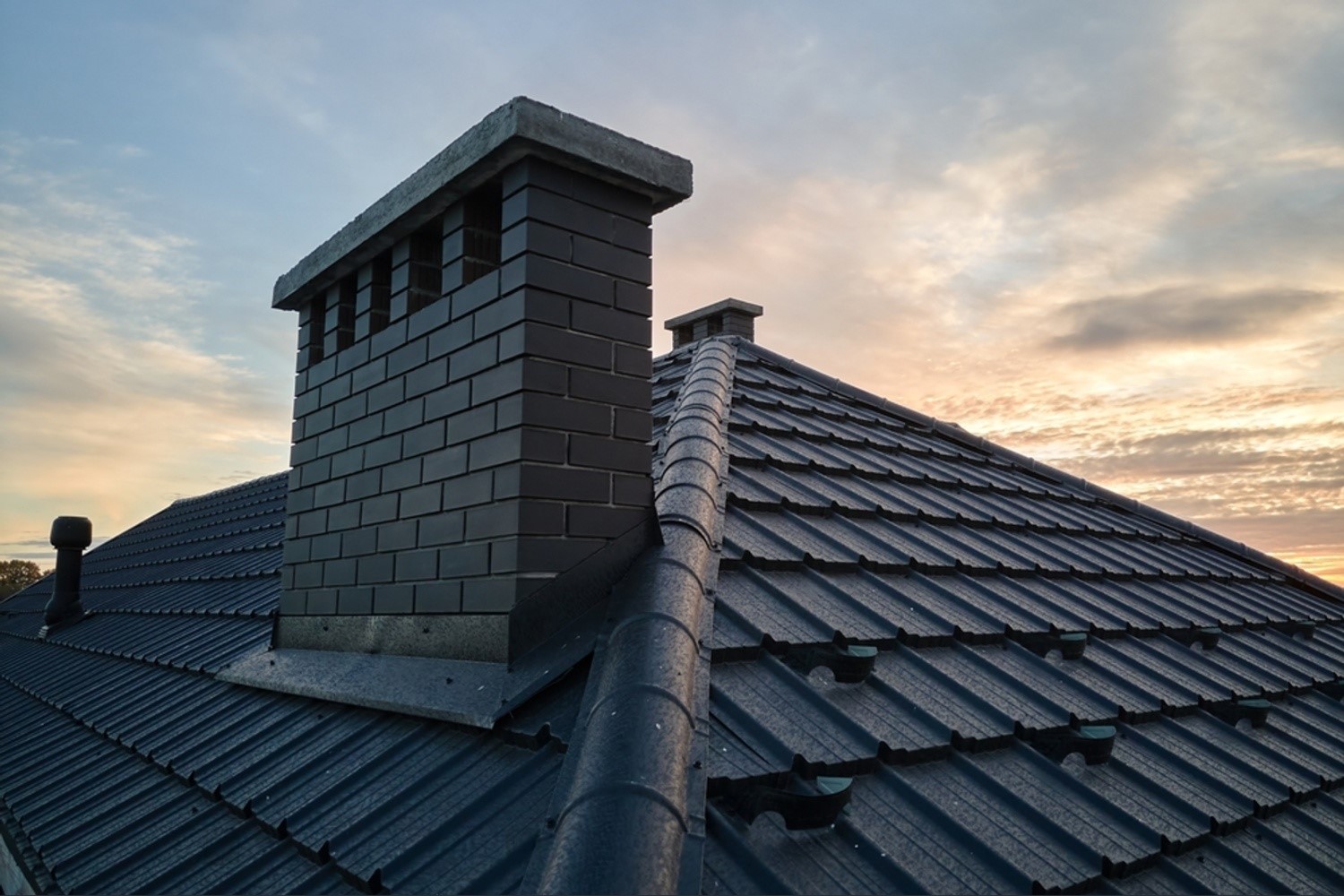 a chimney and roof at sunset or sunrise.